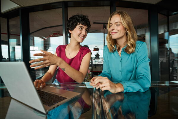 Zwei Frauen im Gespräch vor einem Laptop.