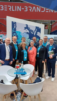 Neun Personen stehen an einem Messestand auf der Messe Expo Real. Sie blicken in die Kamera.