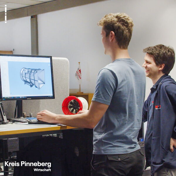 Zwei Männer arbeiten zusammen an einem PC.