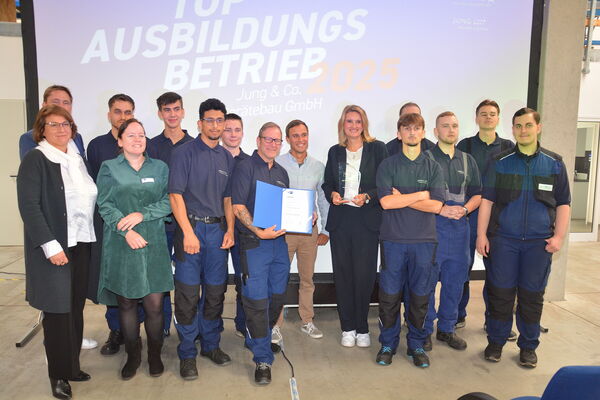 Eine Gruppe von Menschen präsentiert die Urkunde der IHK zum Top-Ausbildungsbetrieb.