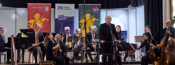 Ein Orchester spielt verschiedene Musikinstrumente auf einer Bühne.