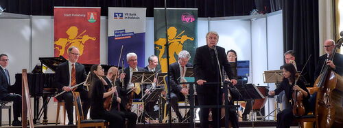 Ein Orchester spielt verschiedene Musikinstrumente auf einer Bühne.