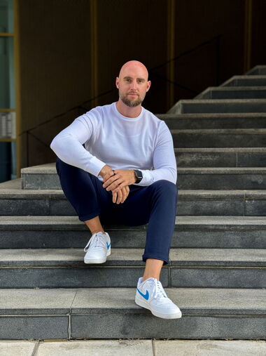 Das Foto zeigt Christian Dralle auf einer Eingangstreppe zu einer Verwaltung sitzend. Er schaut freundlich in die Kamera und strahlt Selbstsicherheit und Aktivität aus. Foto: DR Beratung & Management