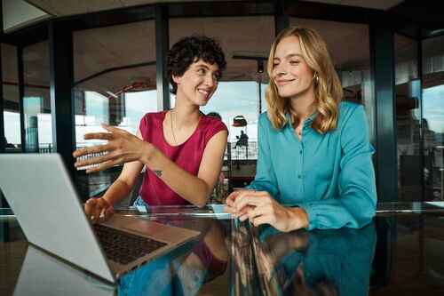 Zwei Frauen im Gespräch vor einem Laptop.