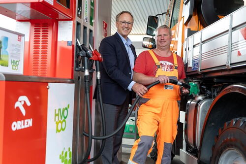 Zwei Personen betanken einen LKW an einer Tankstelle.