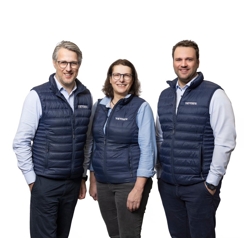 Zwei Männer und eine Frau stehen lächelnd nebeneinander.