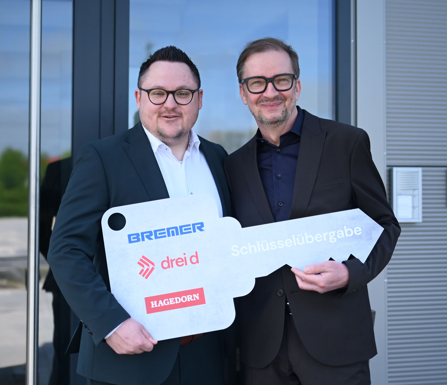 Die drei-d Geschäftsführer vor dem Neubaueingang mit dem symbolischen Schlüssel.