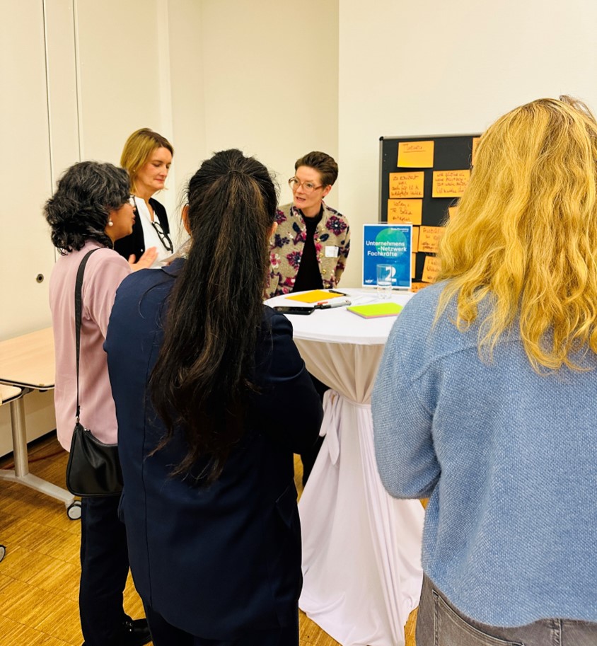 Mehrere Personen diskutieren vor einer Stellwand.