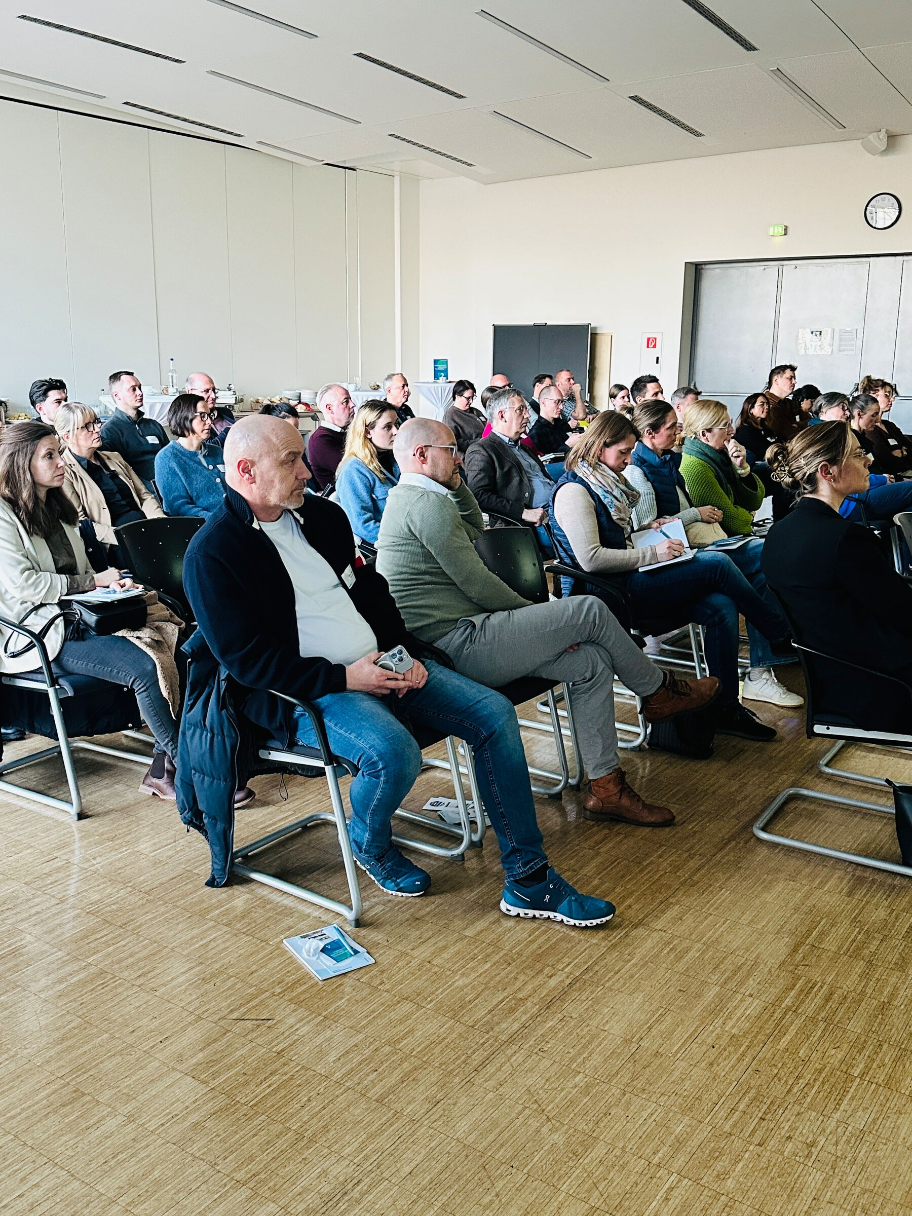Eine Gruppe von Menschen sitzt in einem Veranstaltungsraum in Stuhlreihen.