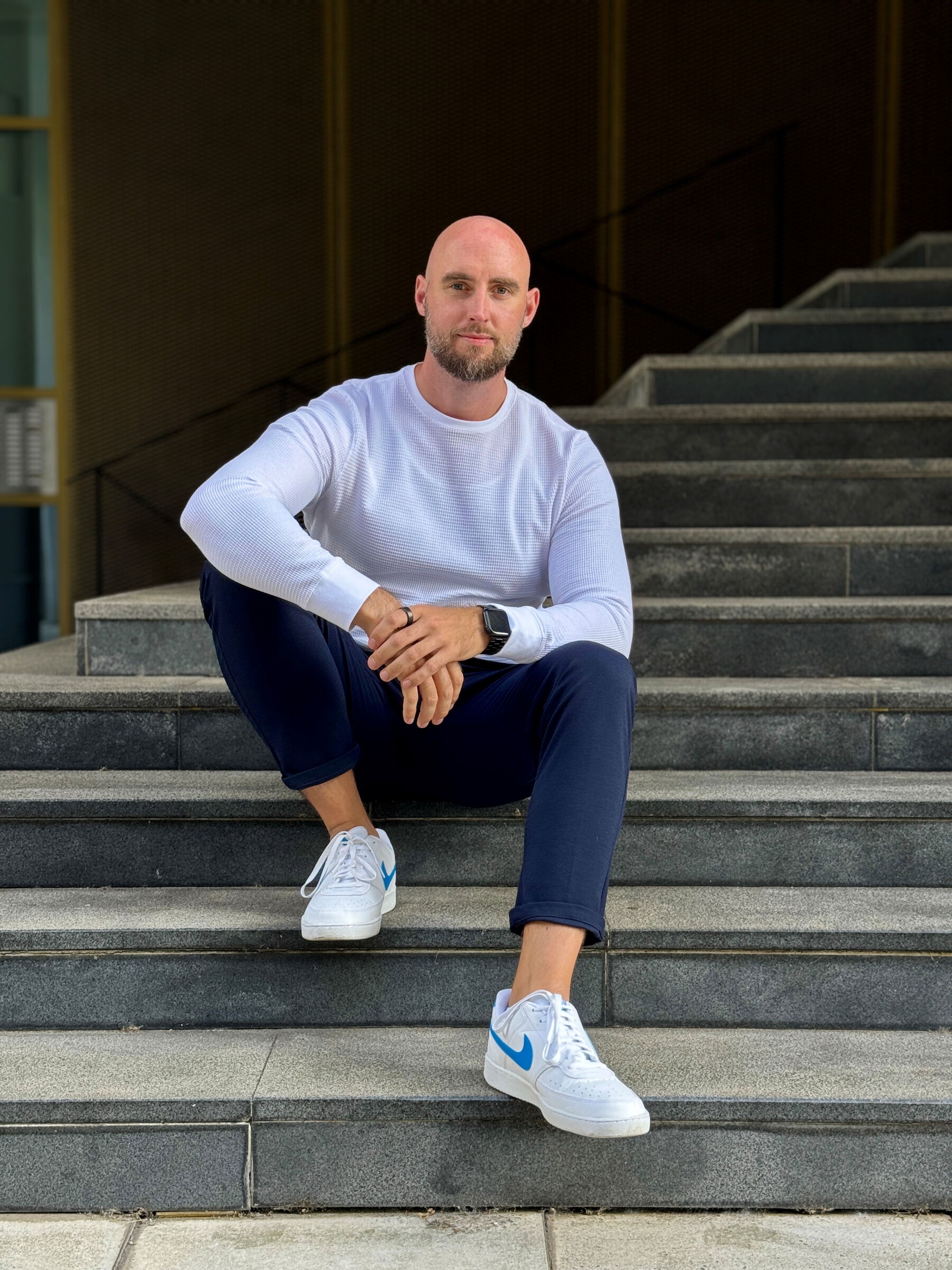 Das Foto zeigt Christian Dralle auf einer Eingangstreppe zu einer Verwaltung sitzend. Er schaut freundlich in die Kamera und strahlt Selbstsicherheit und Aktivität aus. Foto: DR Beratung & Management