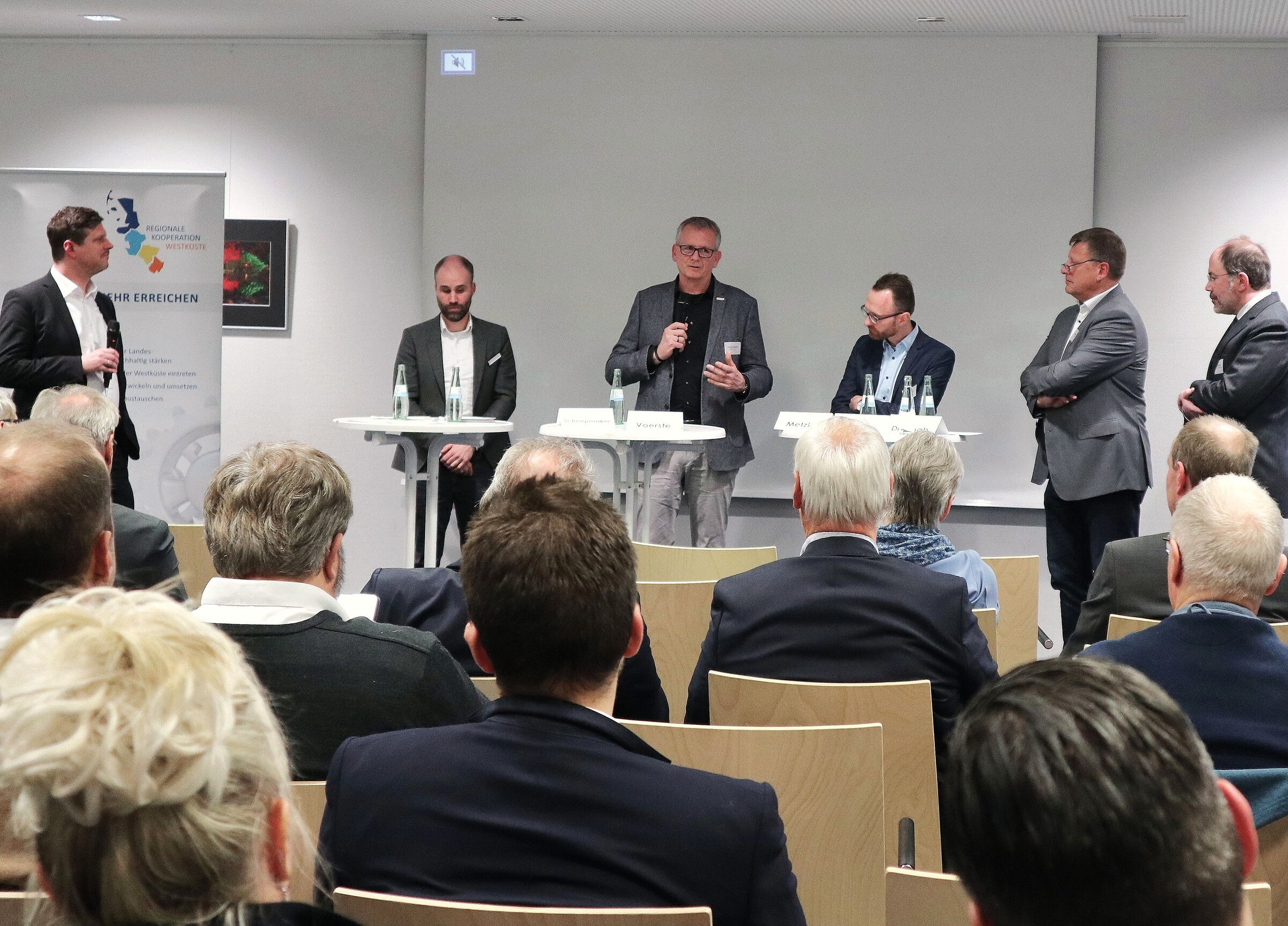 Publikum von hinten, das den Worten von Gemeindevertretern auf dem Podium, so auch Pinnebergs Bürgermeister Thomas Voerste, lauscht.