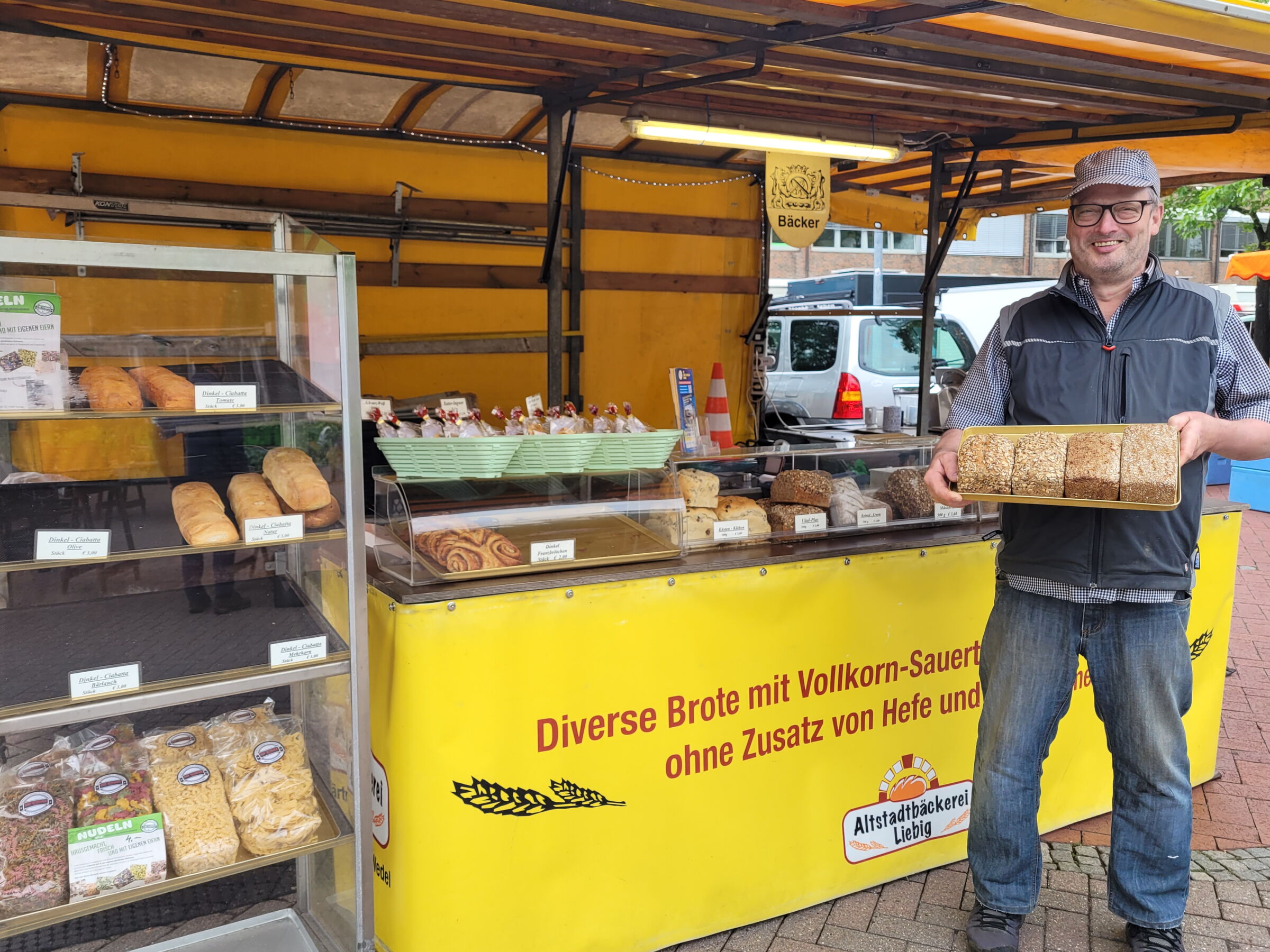 Stephan Liebig präsentiert vor seinem Markststand verschiedene Brote.